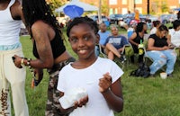 a young girl eating ice cream at an outdoor event