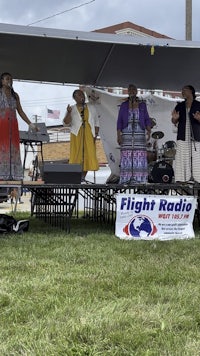 a group of women singing on stage in front of a sign that says flight radio